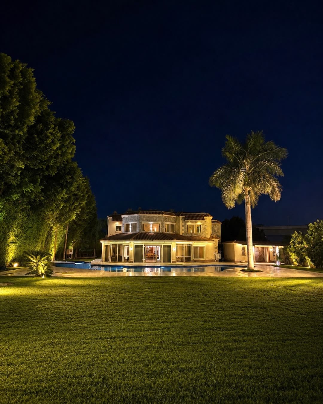 The villa and lawn lit up at night